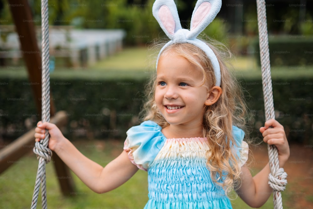 a little girl with bunny ears on a swing