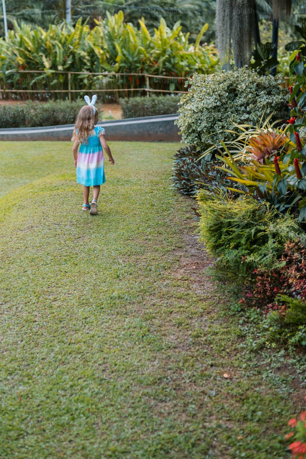 a little girl walking through a lush green park