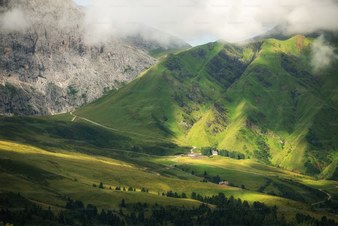 a lush green valley surrounded by mountains under a cloudy sky
