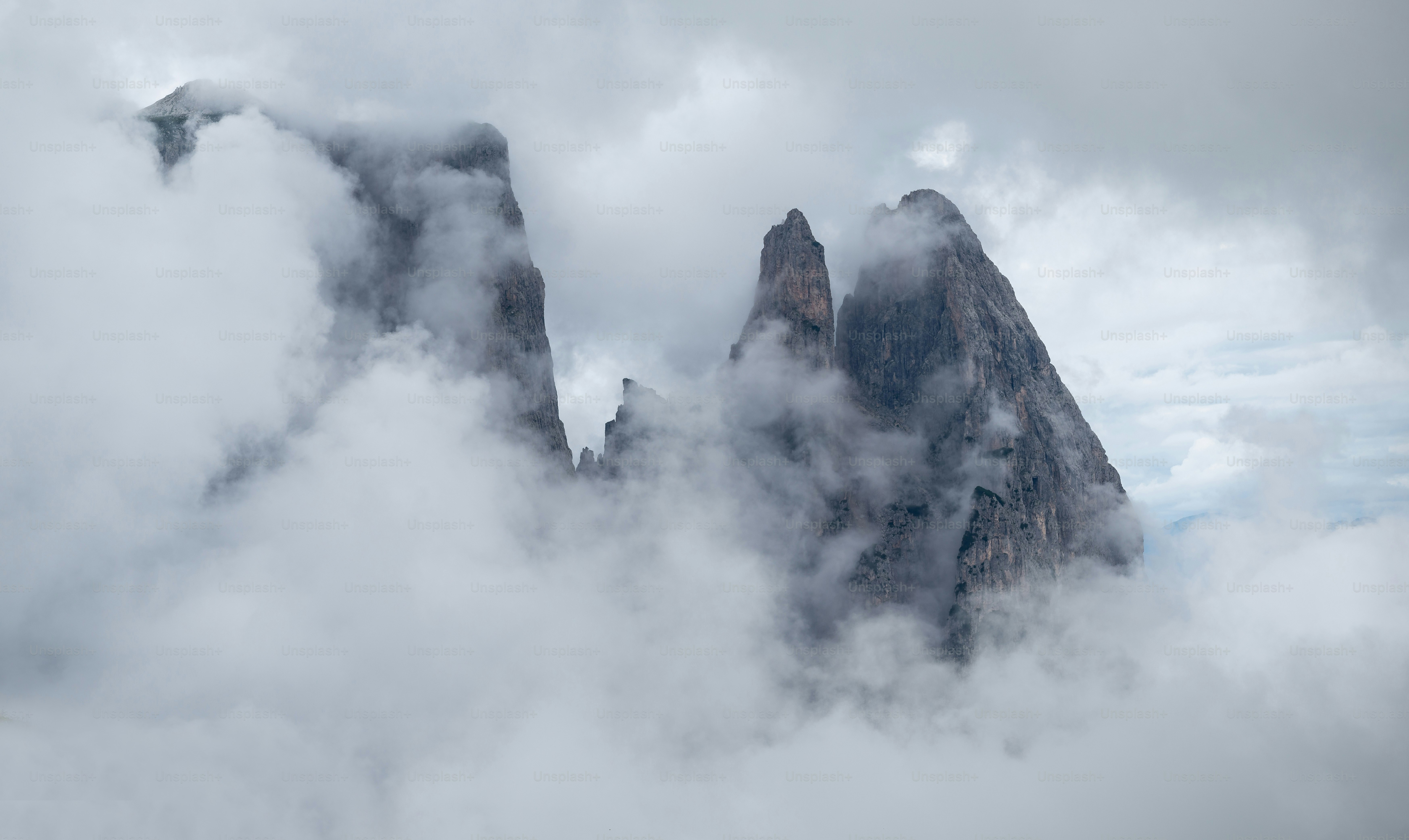 Un groupe de montagnes entouré de nuages dans le ciel