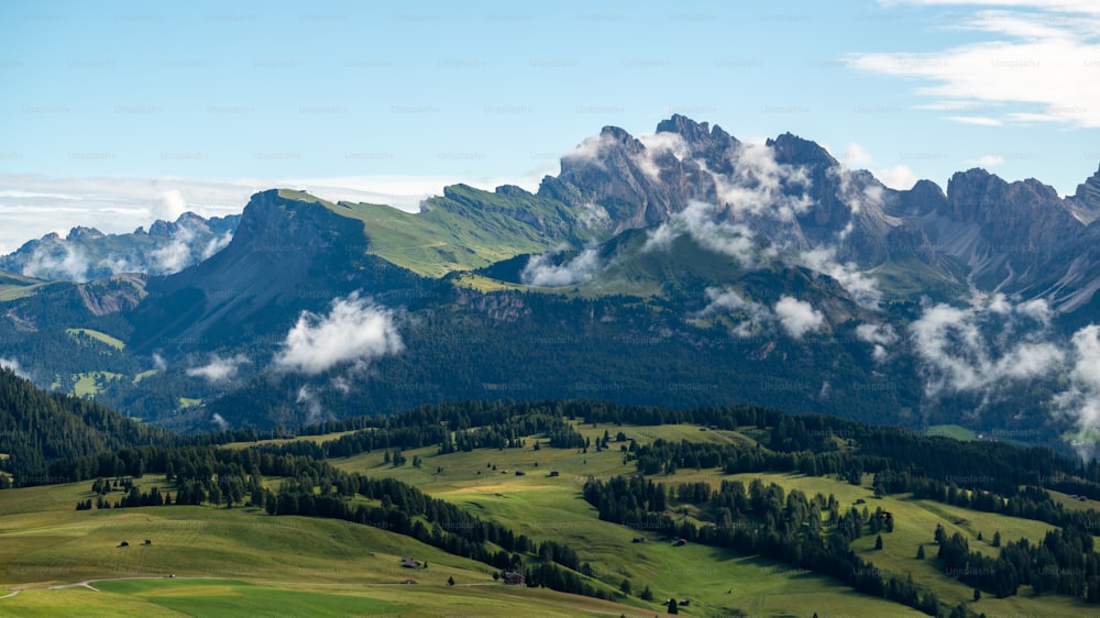 the mountains are covered in clouds and green grass