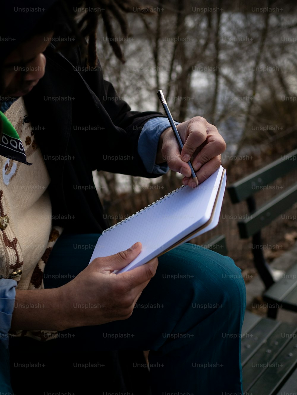 Una persona sentada en un banco escribiendo en un pedazo de papel
