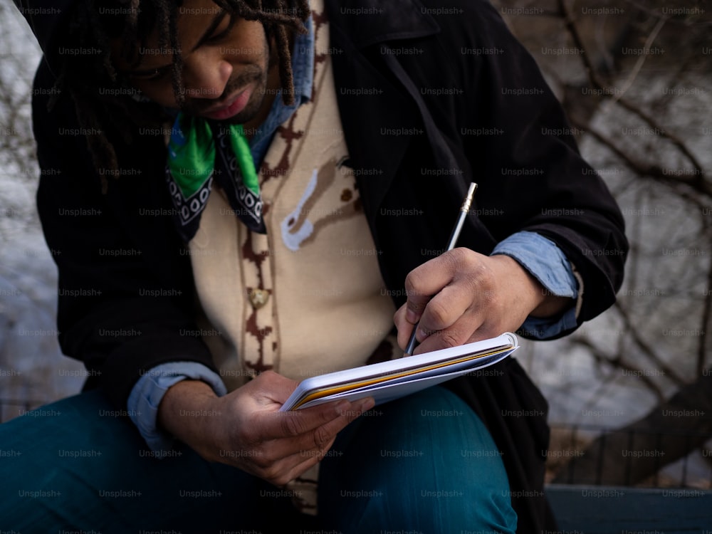 Un homme avec des dreadlocks écrivant sur un cahier