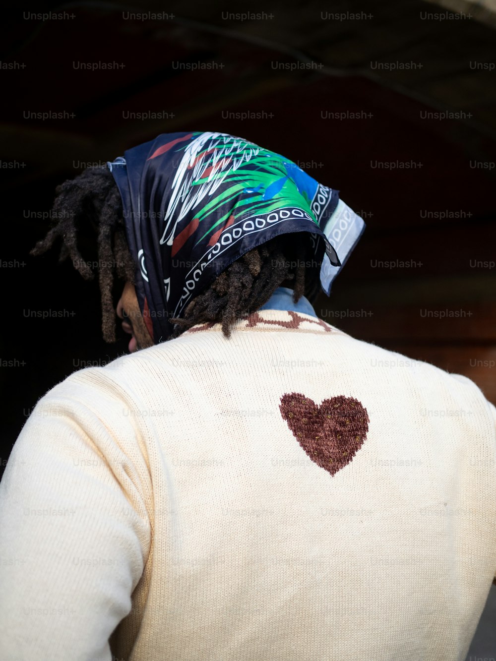 a man with dreadlocks wearing a sweater with a heart on it