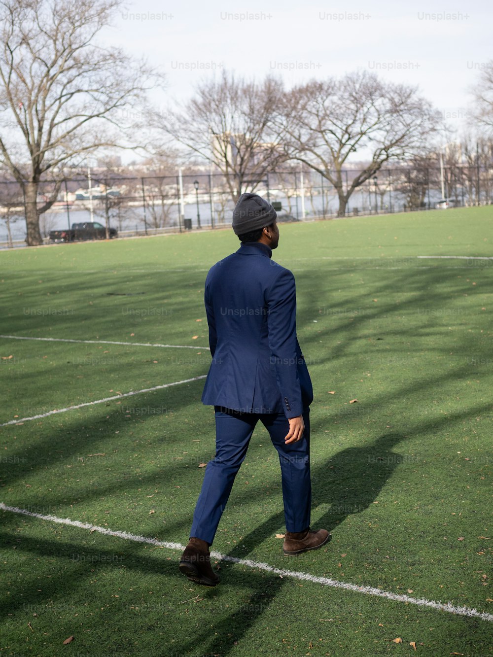 a man in a suit and hat walking across a field
