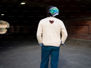 a man standing in a tunnel wearing a sweater with a heart on it