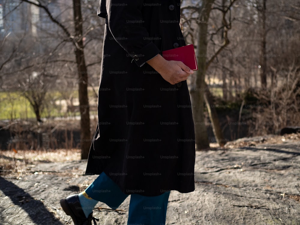 a woman in a black coat holding a red purse