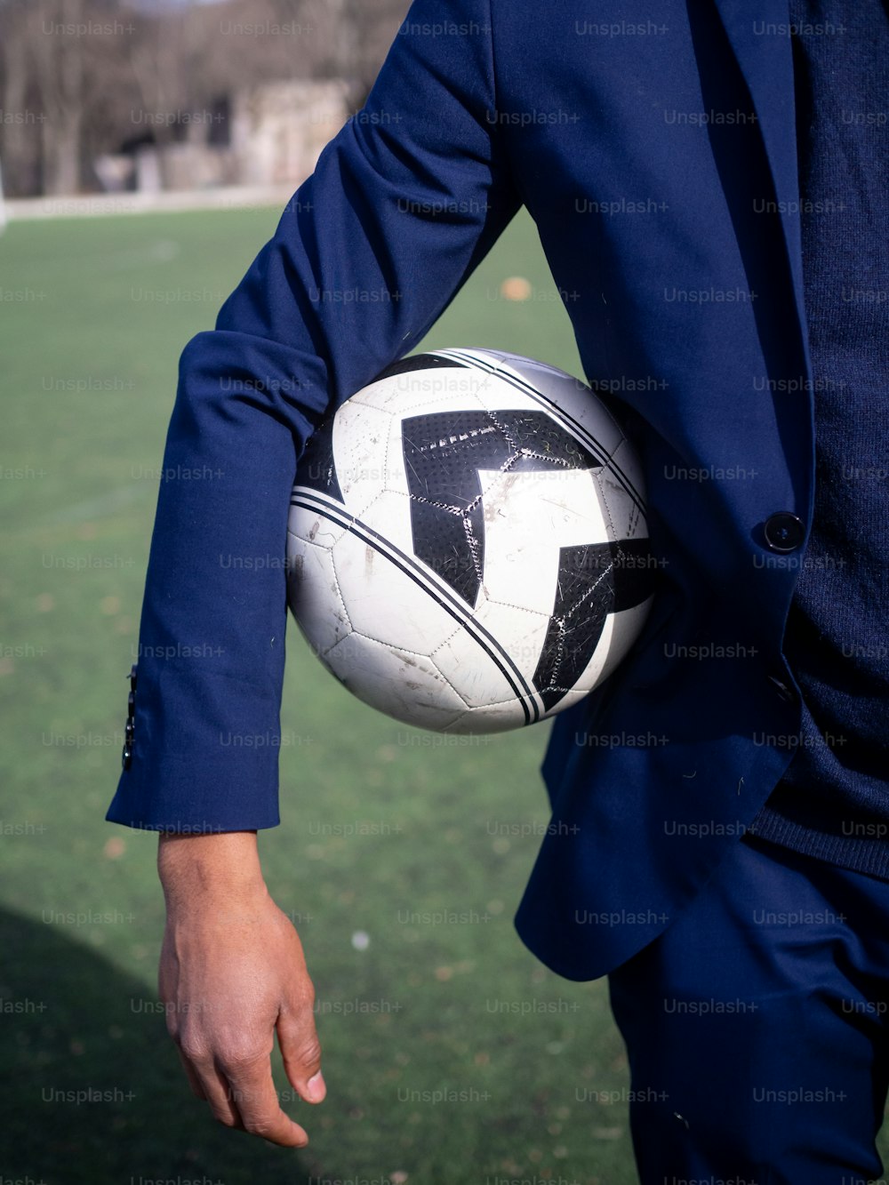 Un uomo in giacca e cravatta che tiene un pallone da calcio