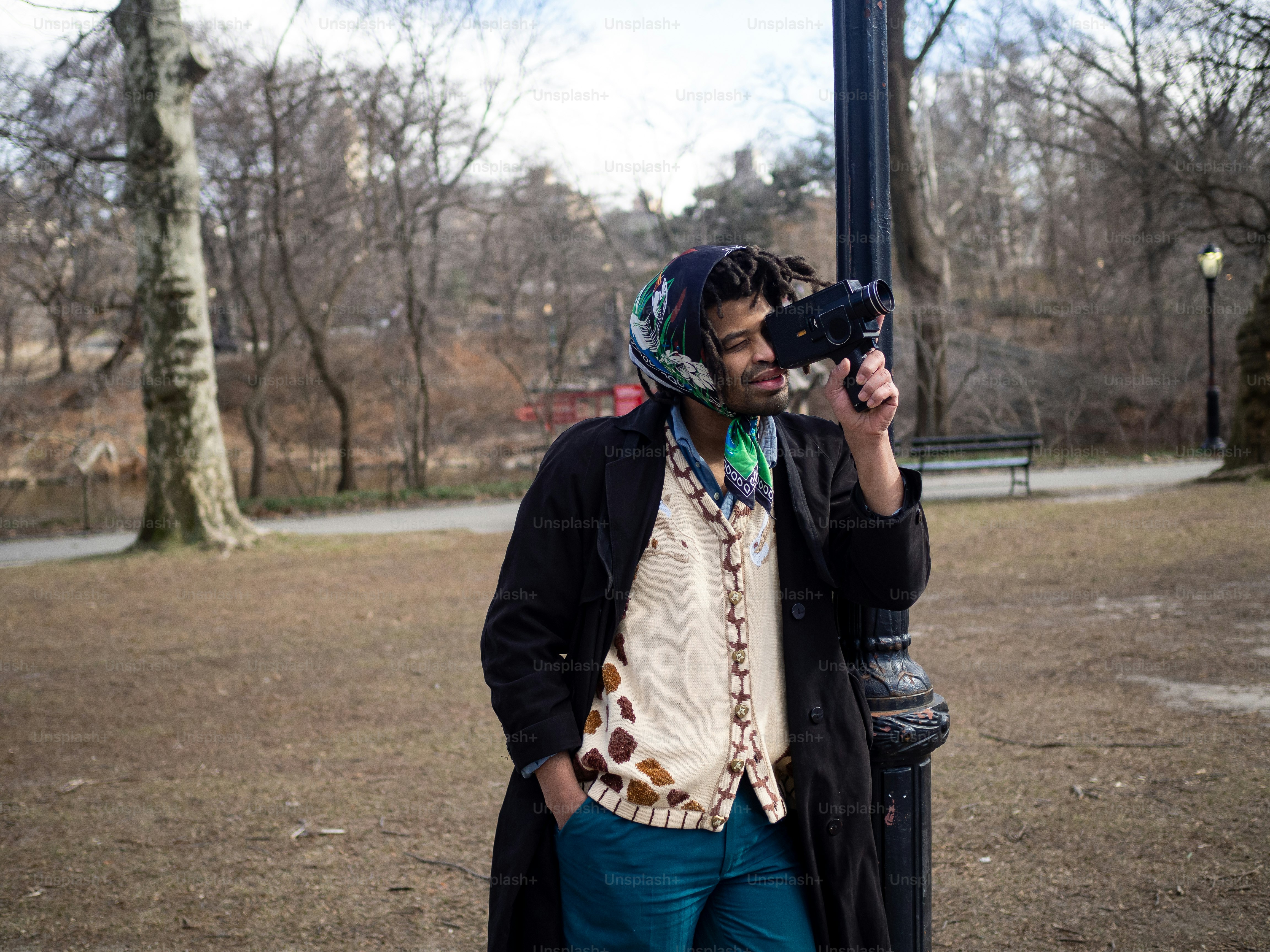 a man standing next to a pole holding a camera