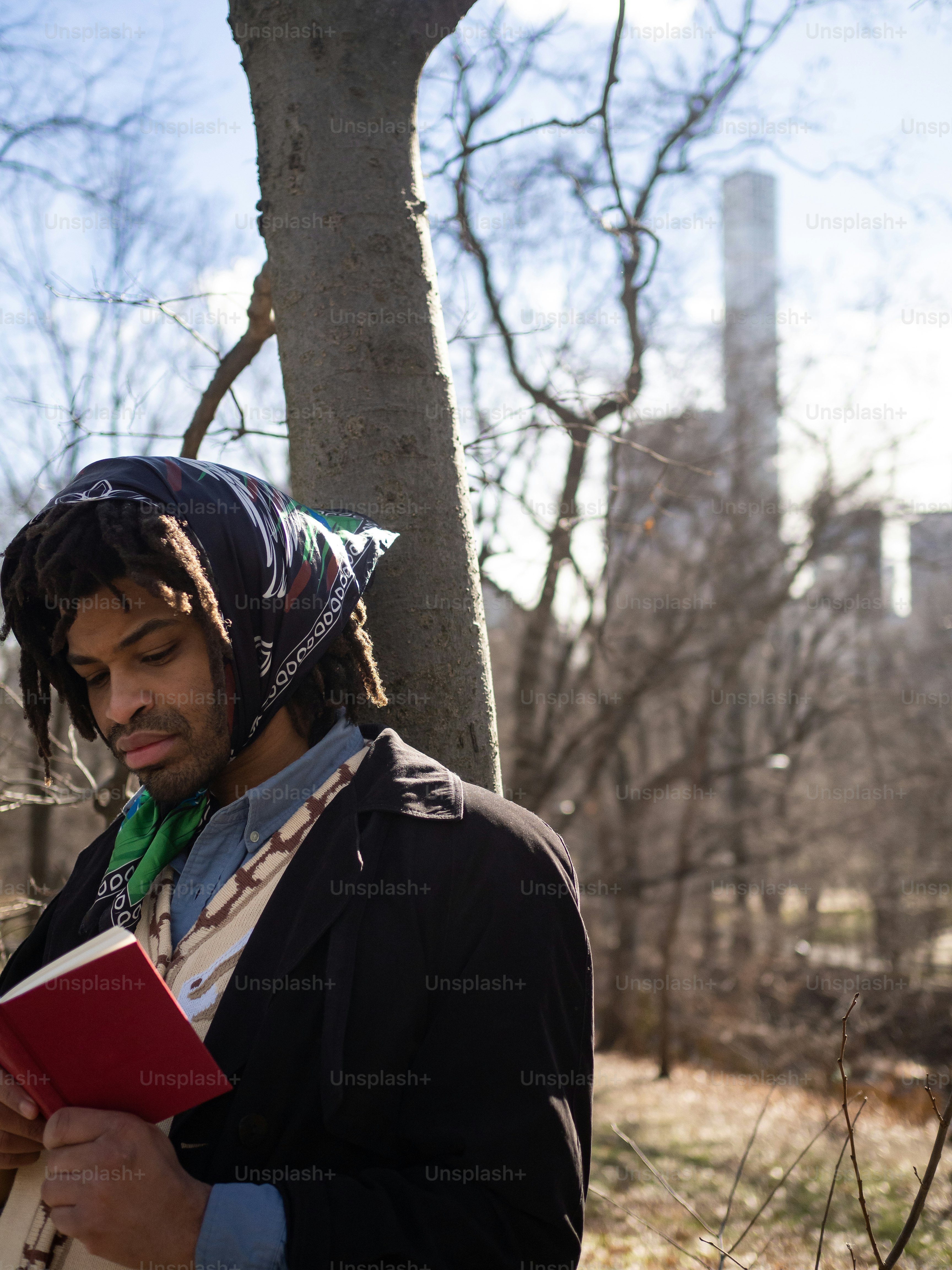 a man standing next to a tree holding a book