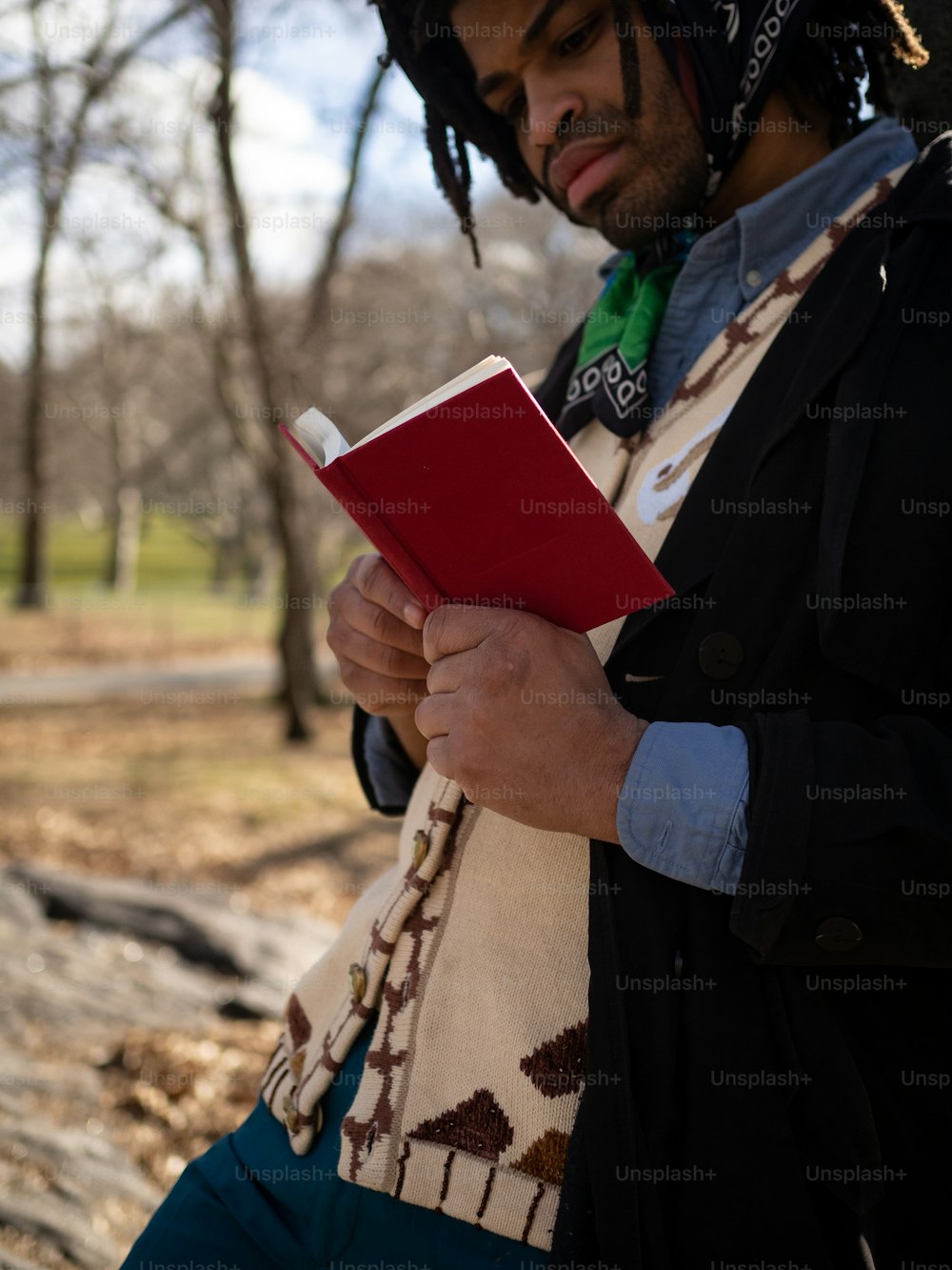 a man with dreadlocks holding a red book