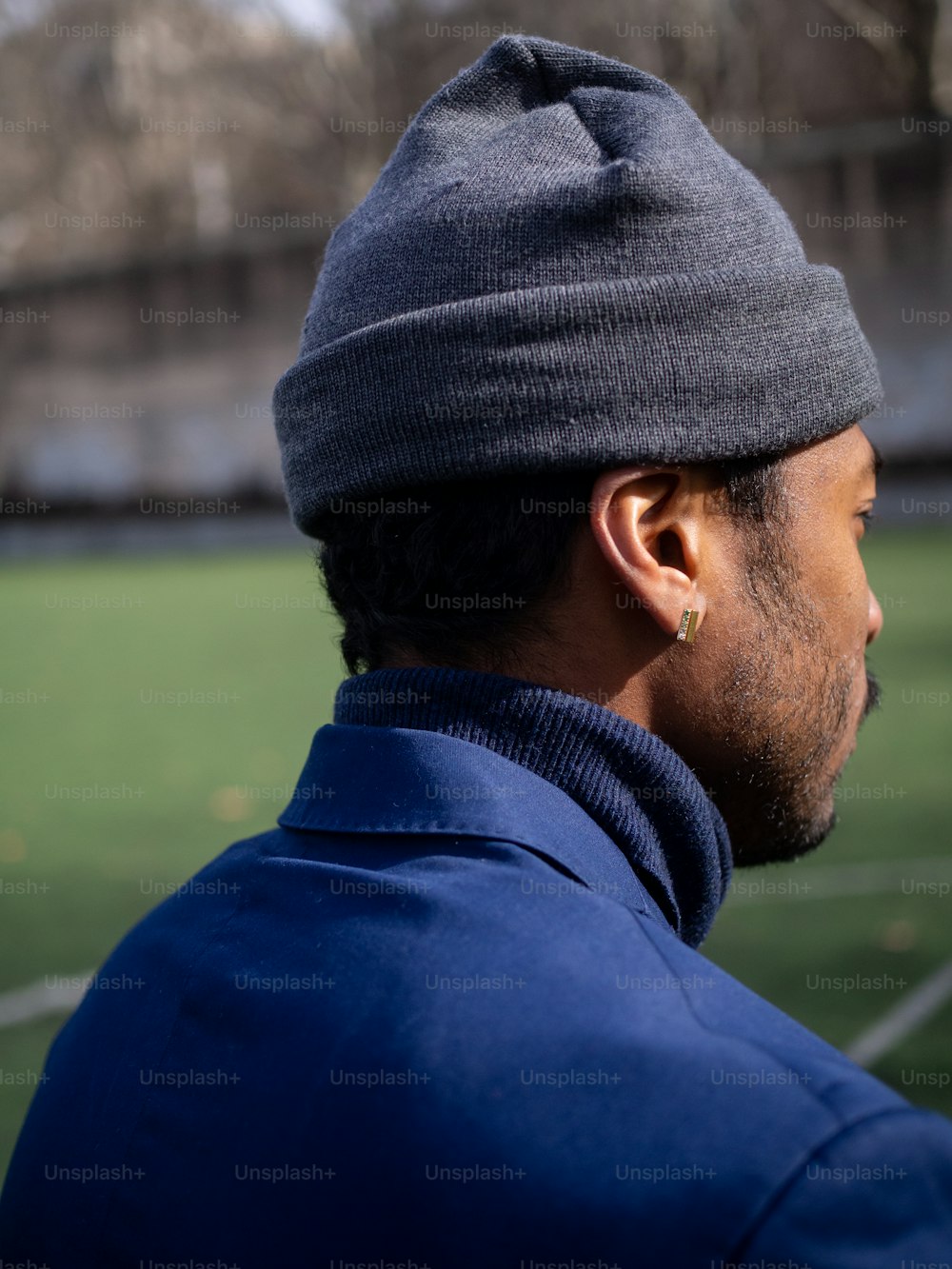 a man wearing a beanie looking at a soccer field