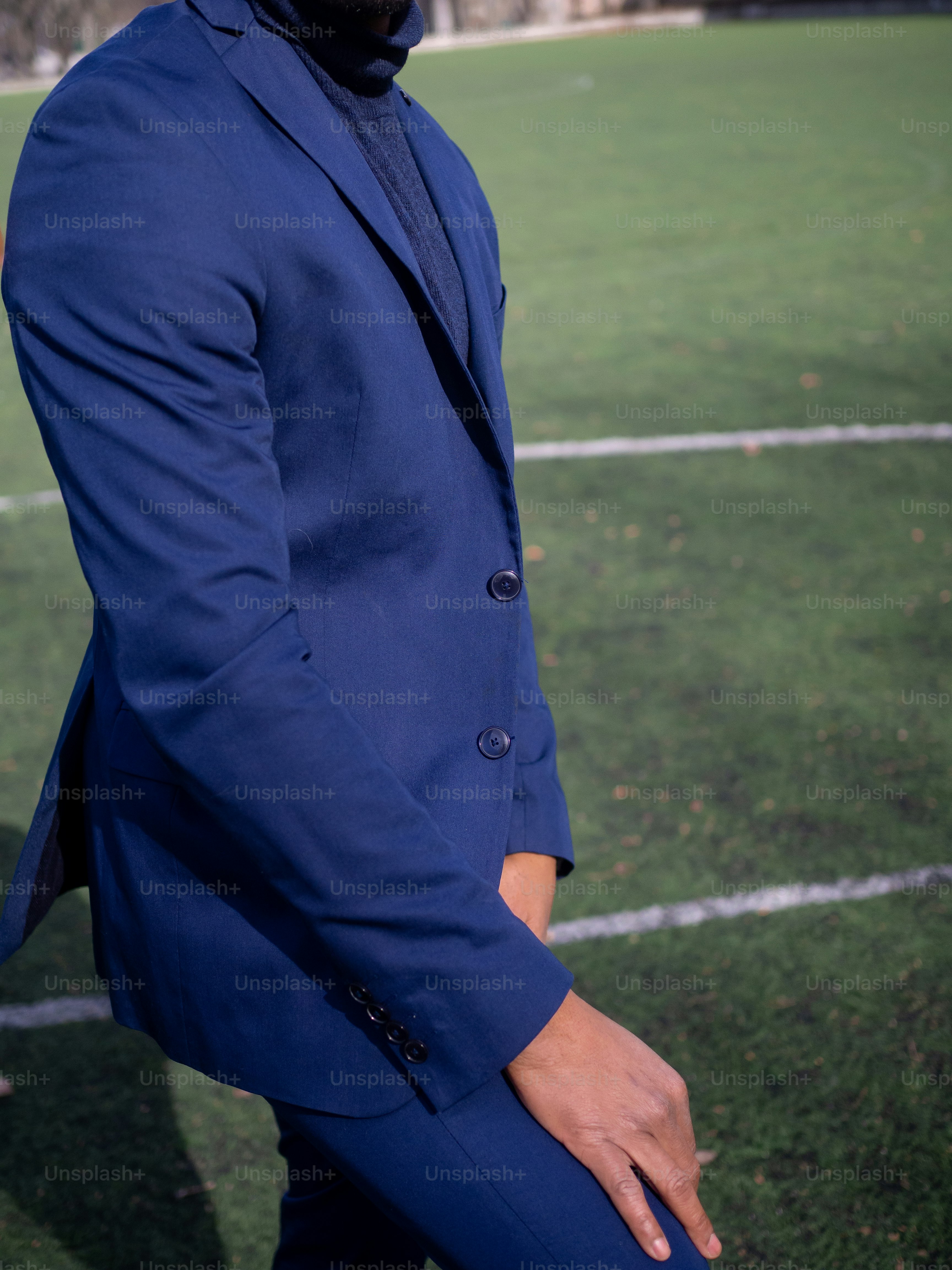 a man in a blue suit standing on a soccer field
