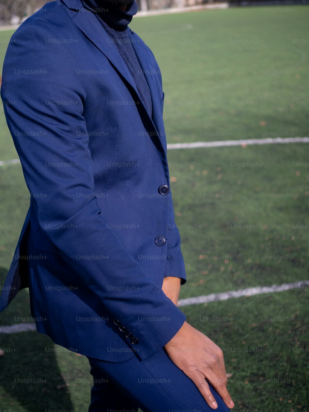 サッカー場に立つ青いスーツを着た男