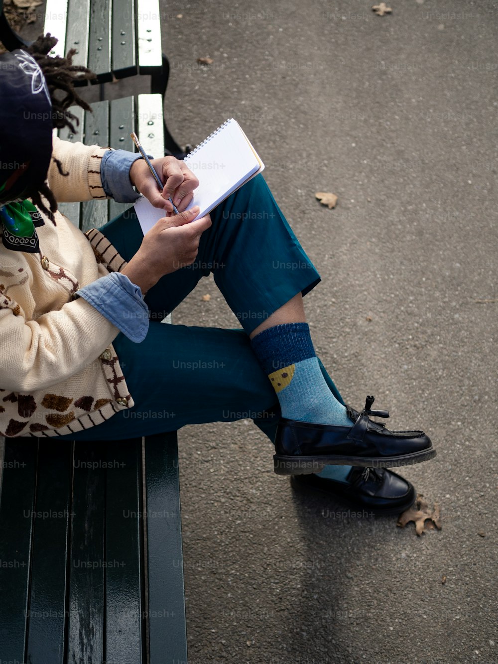 uma pessoa sentada em um banco escrevendo em um pedaço de papel
