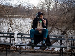 a man sitting on a bench next to a river