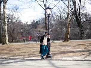 um homem de pé ao lado de uma luz de rua em um parque