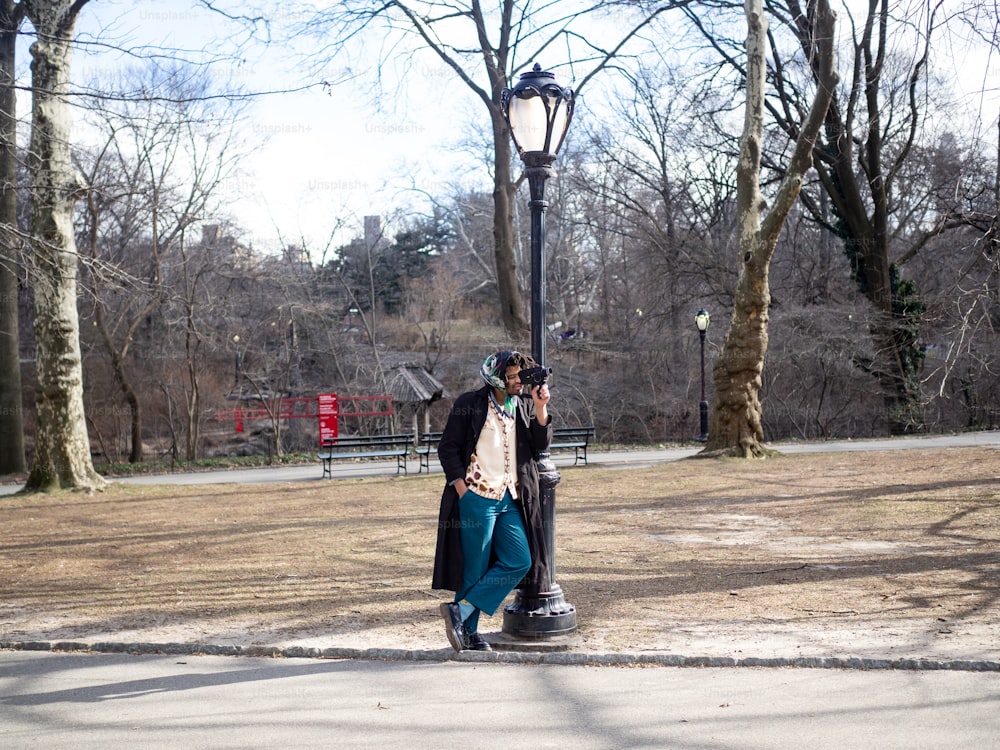 Ein Mann steht neben einer Straßenlaterne in einem Park