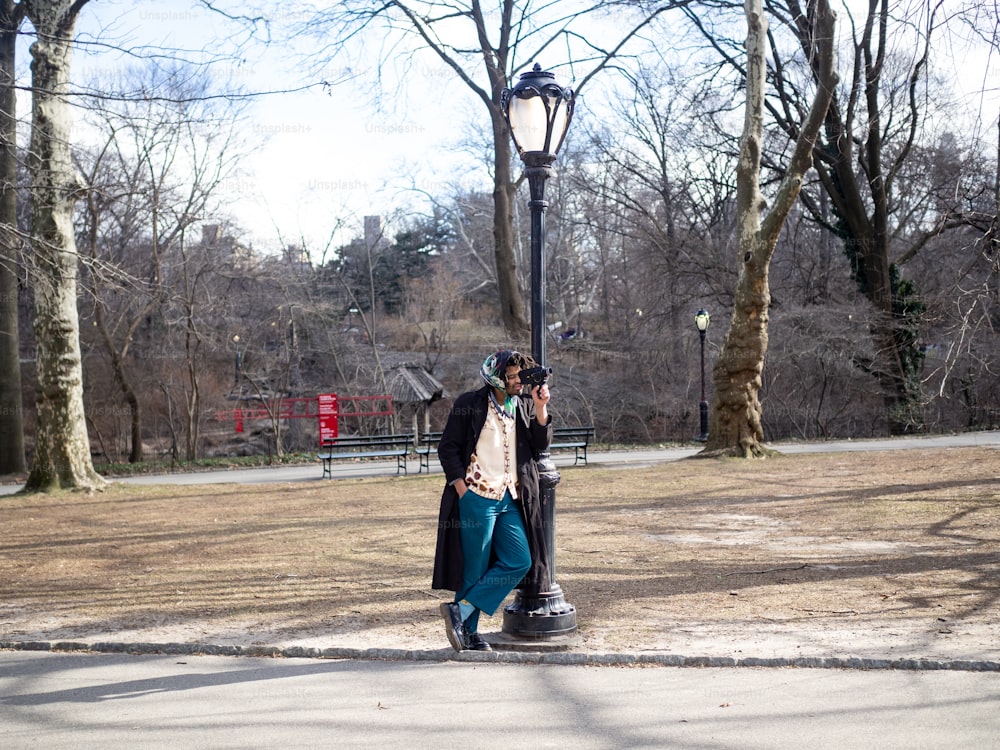 a man standing next to a street light in a park