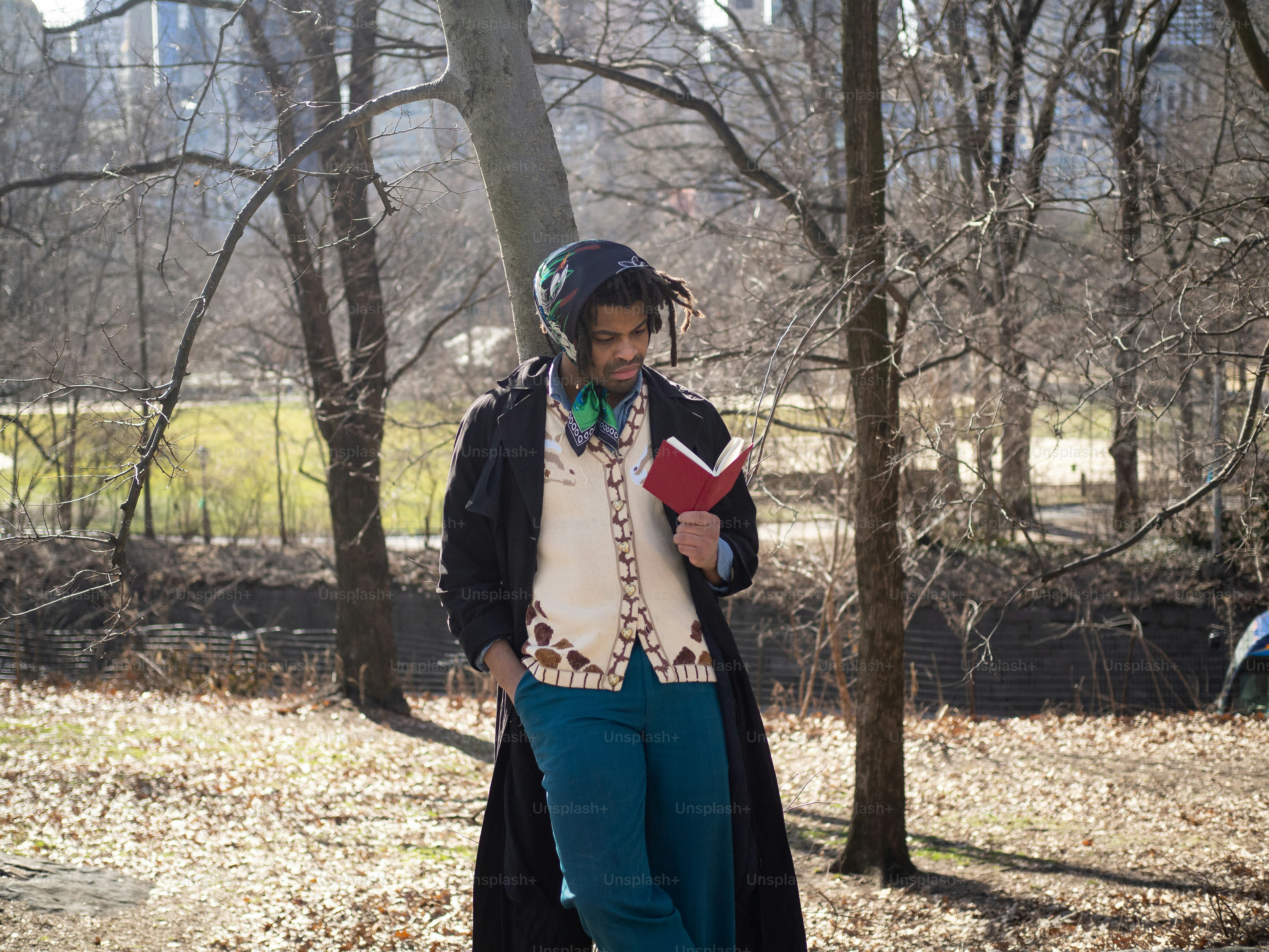 a man with a book in his hand walking through a park