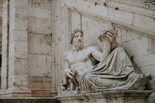 a statue of a man with a beard sitting on a ledge