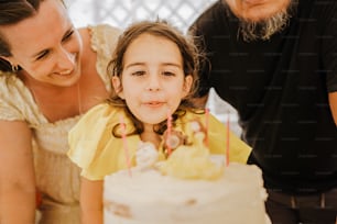 a little girl sitting in front of a white cake