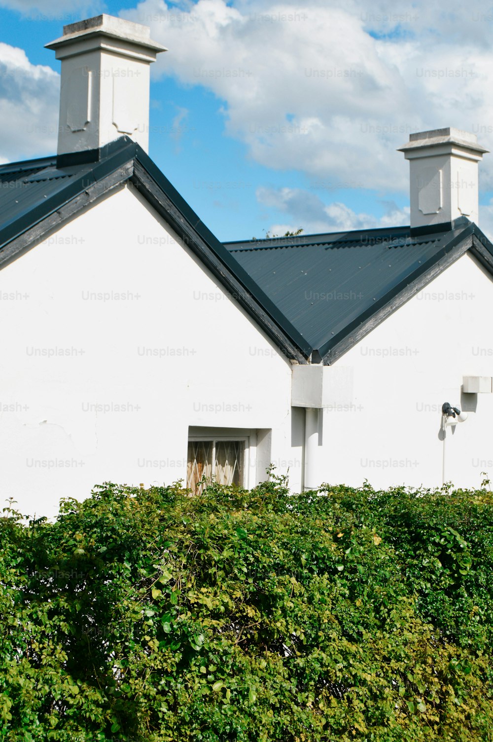 uma casa branca com um telhado preto e duas chaminés