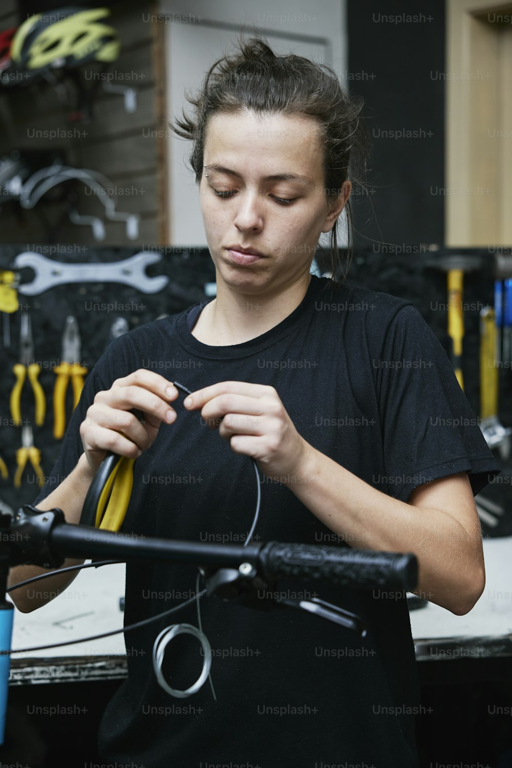 a woman in a black shirt working on a bicycle