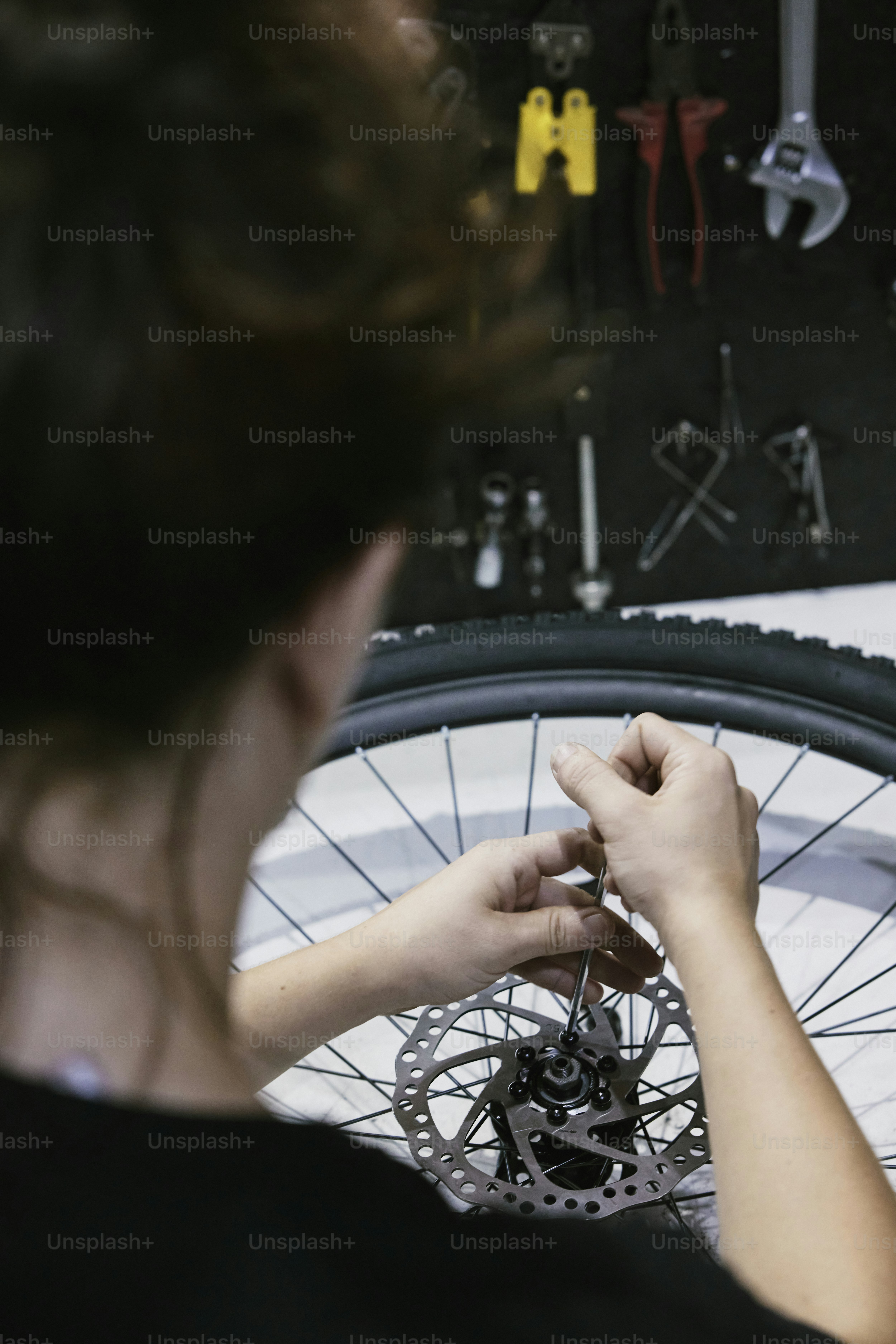 a woman is working on a bicycle wheel