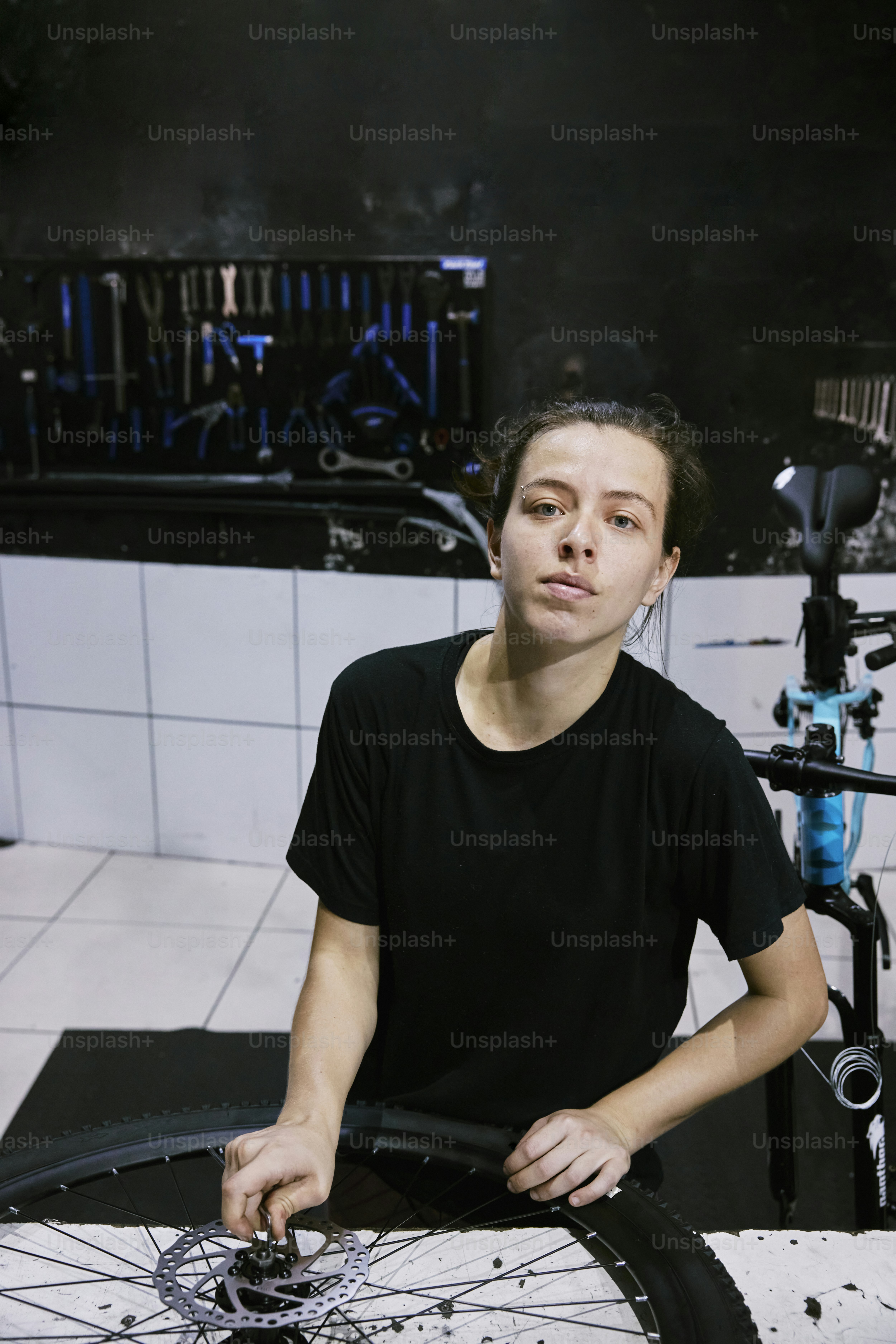 a woman sitting in front of a bicycle wheel