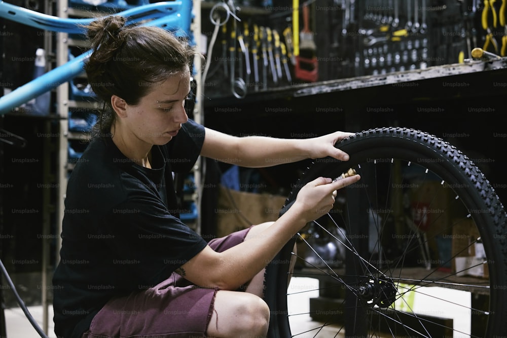 a woman is working on a bicycle tire