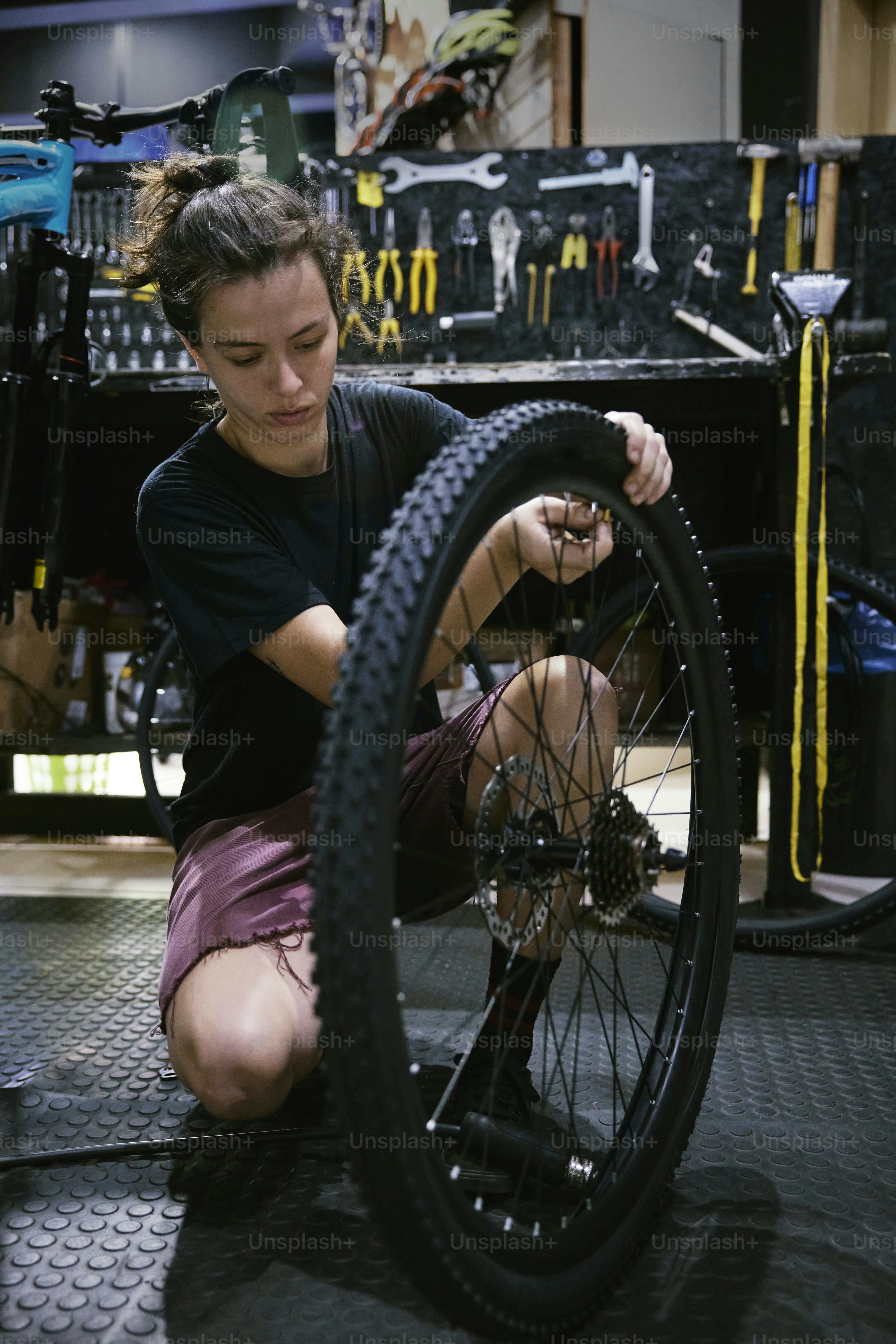 Eine Frau bei der Arbeit an einem Fahrradreifen in einer Garage