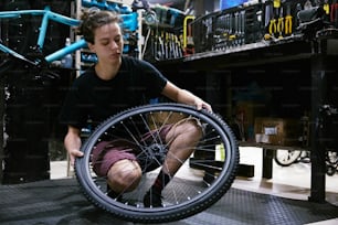 a young man working on a bicycle wheel