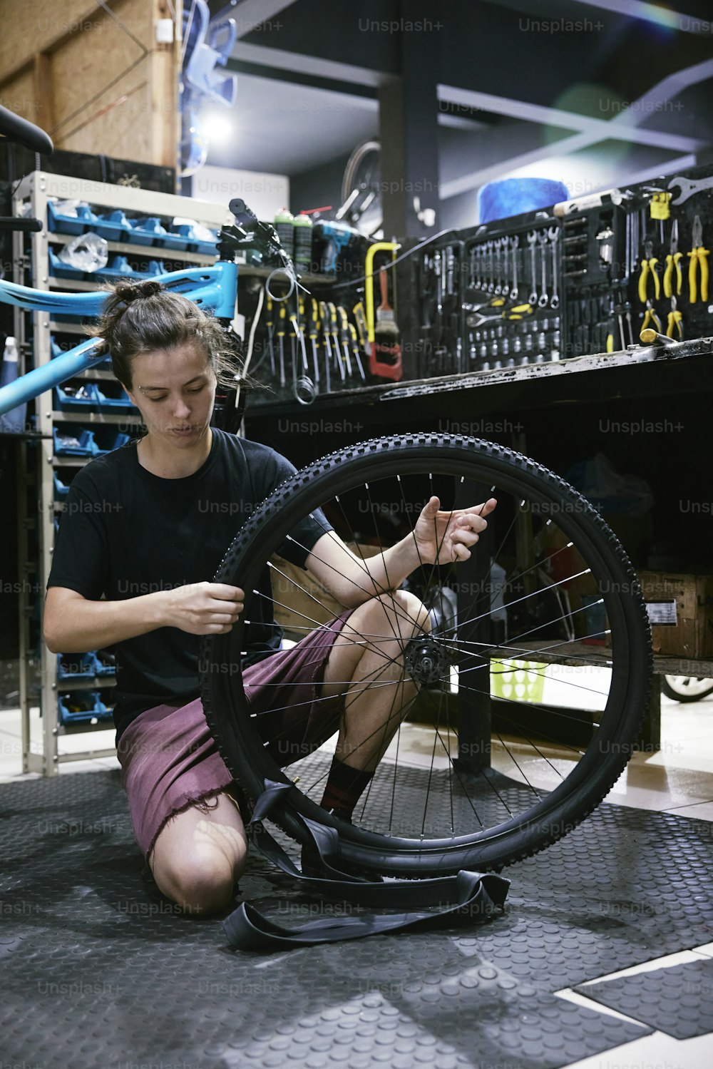 ガレージで自転車の車輪で作業している男性