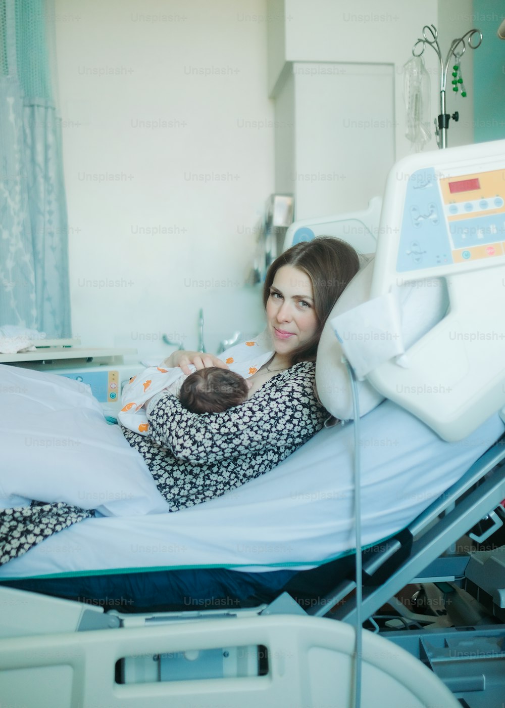 病院のベッドに横たわって赤ん�坊を抱える女性