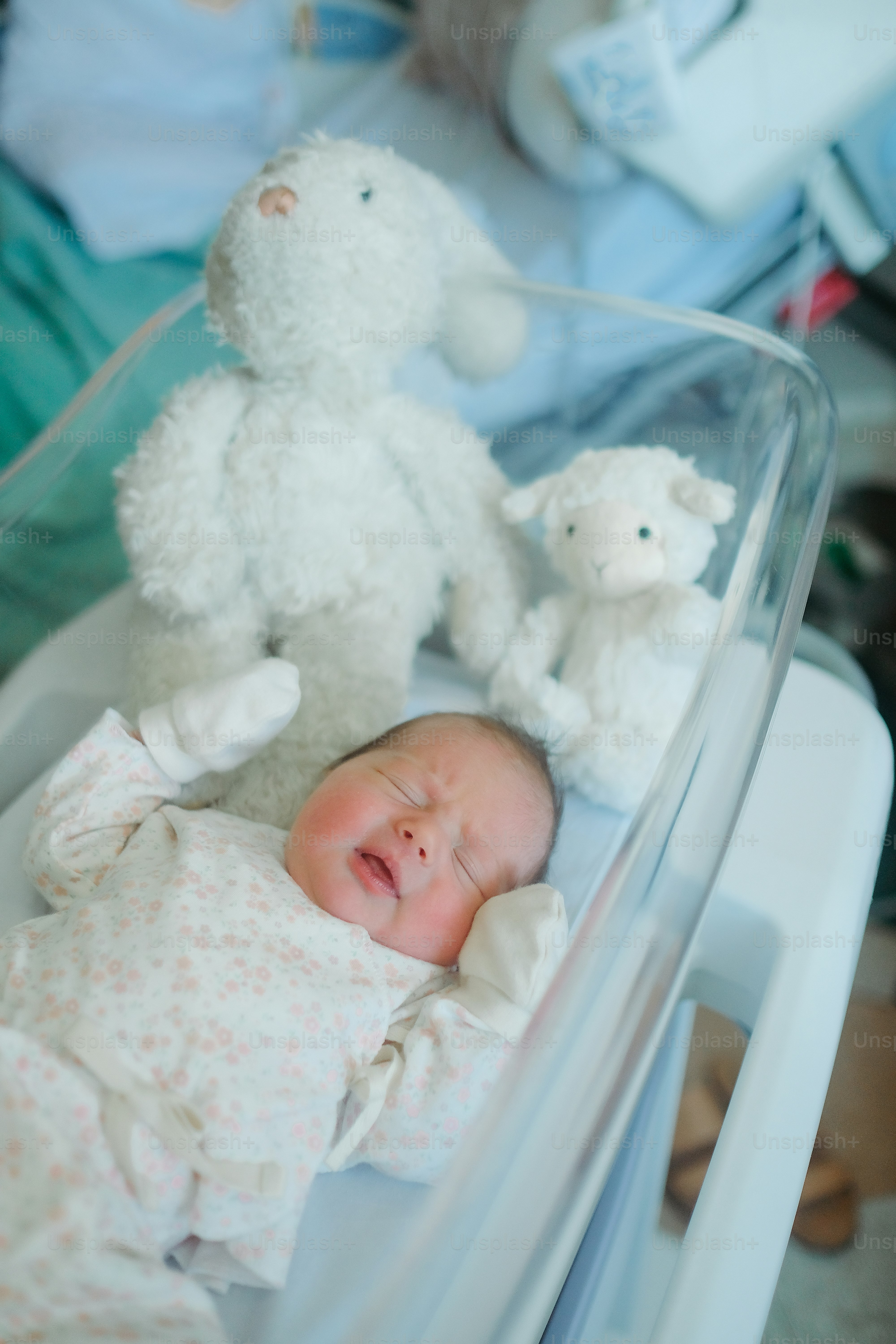 Ein Baby liegt in einer Krippe neben einem weißen Teddybären