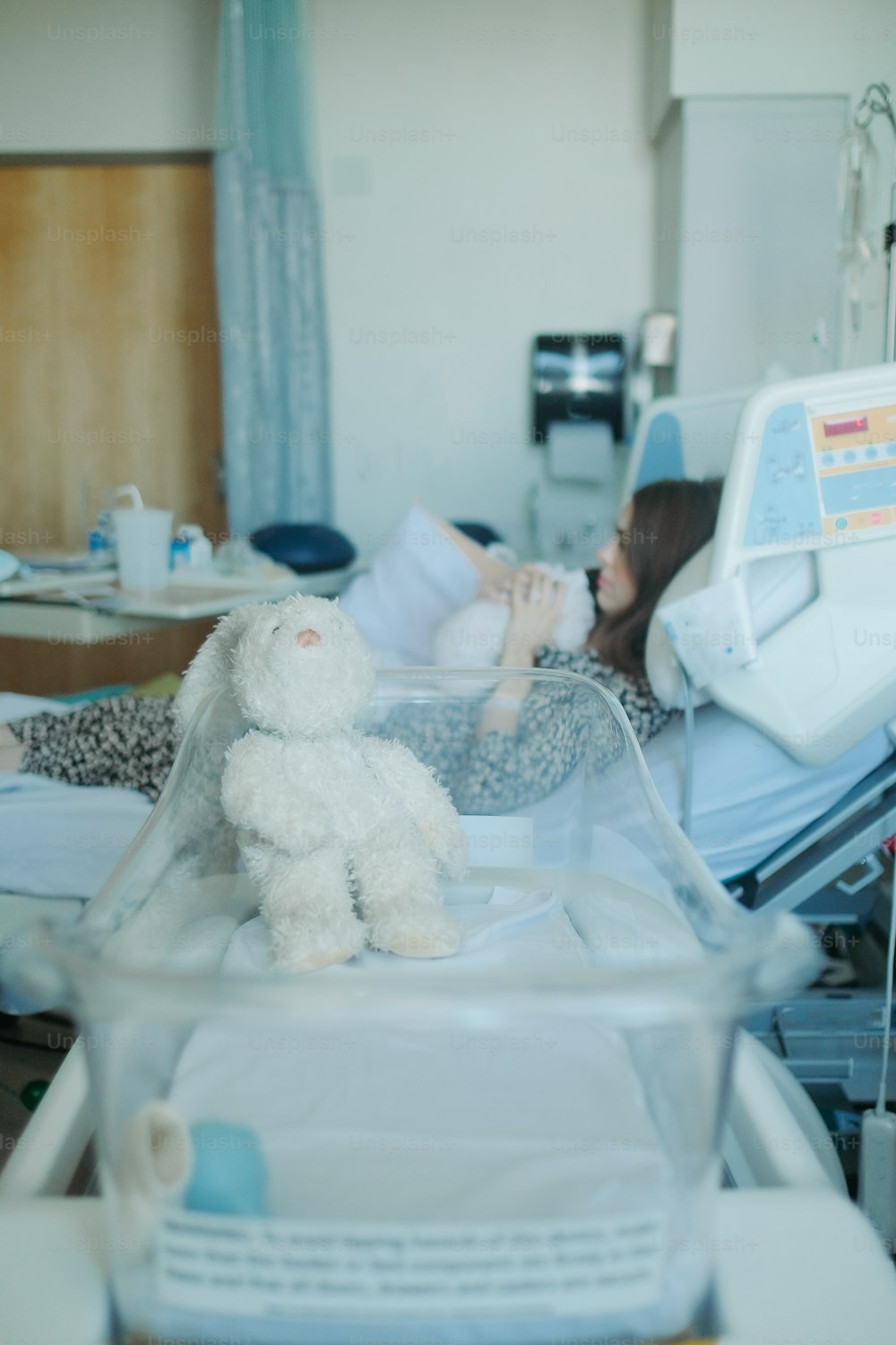 a woman laying in a hospital bed with a stuffed animal