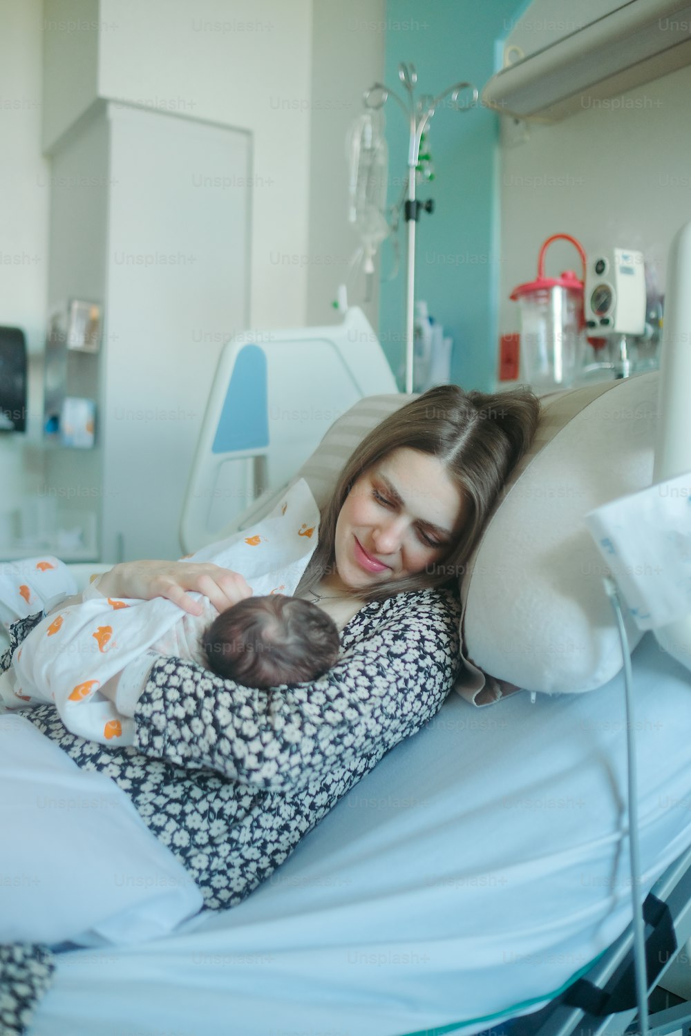 uma mulher que segura um bebê em uma cama de hospital