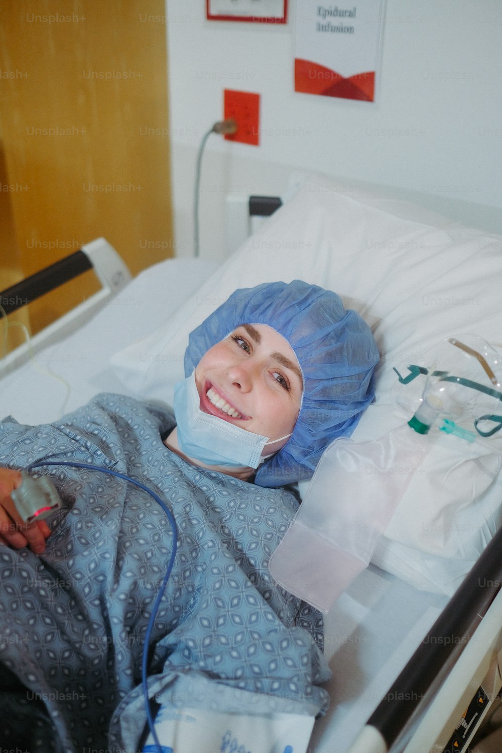 a woman laying in a hospital bed wearing a surgical mask