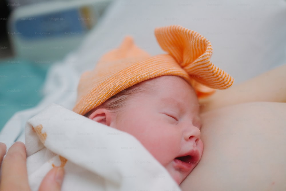 Un bebé con un lazo naranja acostado encima de una cama