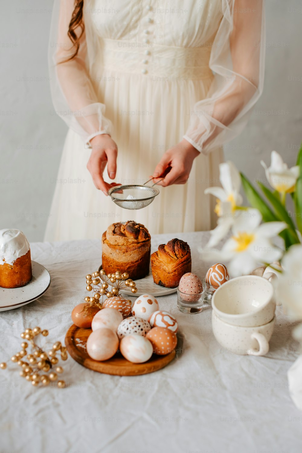 uma mulher em um vestido branco de pé sobre uma mesa cheia de doces