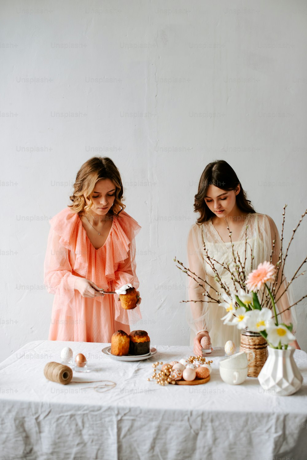 two women standing at a table cutting a cake