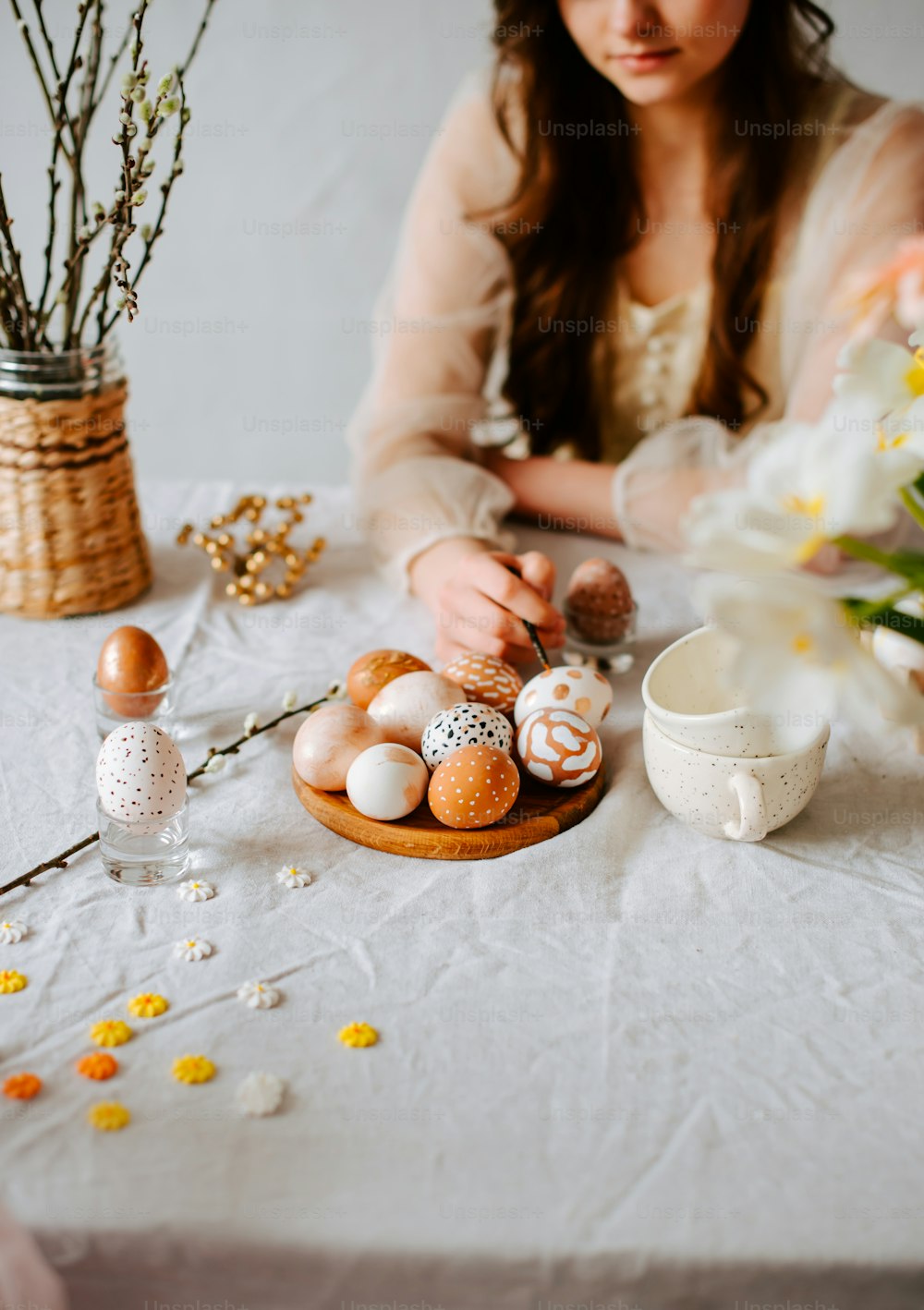 a woman sitting at a table with eggs and flowers