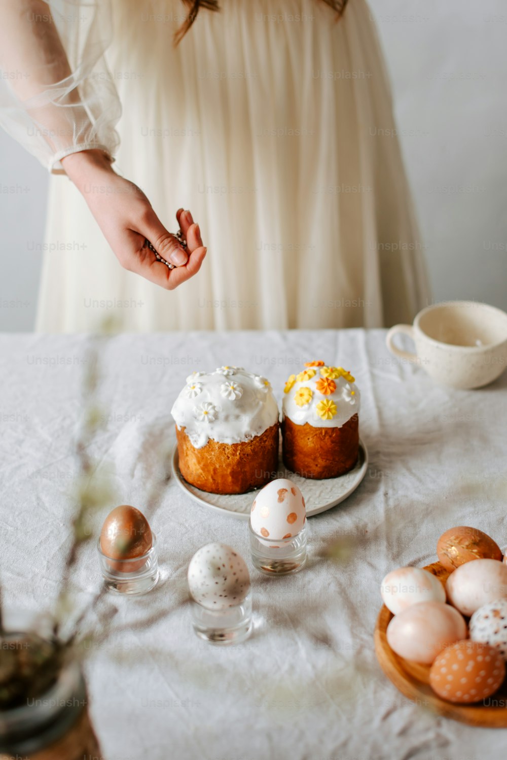 卵でいっぱいのテーブルの隣に立っている白いドレスを着た女性