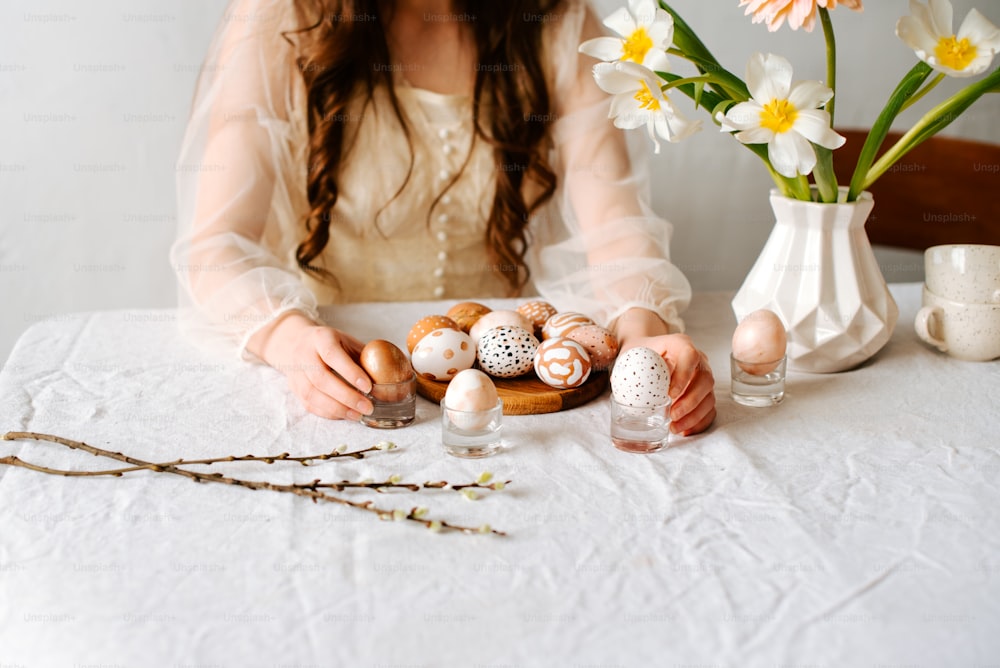 uma mulher sentada em uma mesa com ovos e flores