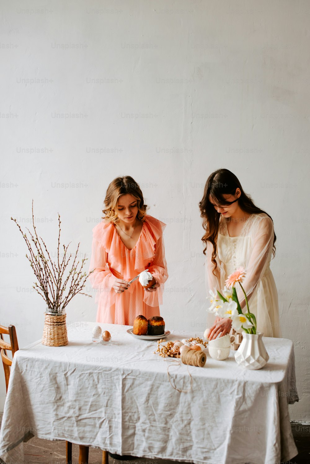 Dos mujeres de pie en una mesa preparando comida