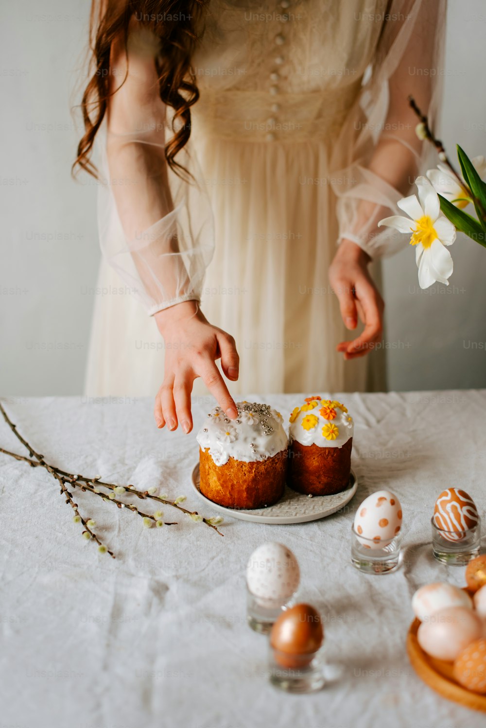 uma mulher em um vestido branco colocando a cereja em um bolo
