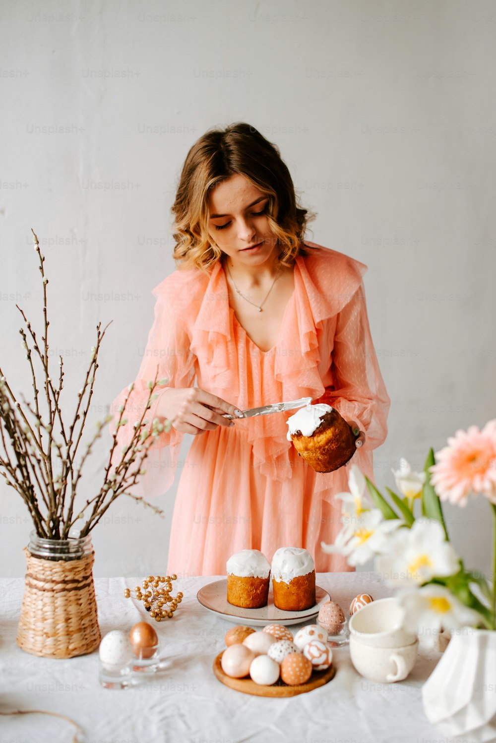 a woman in a pink dress is decorating cupcakes