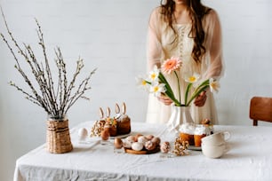 a woman holding a vase of flowers next to a table