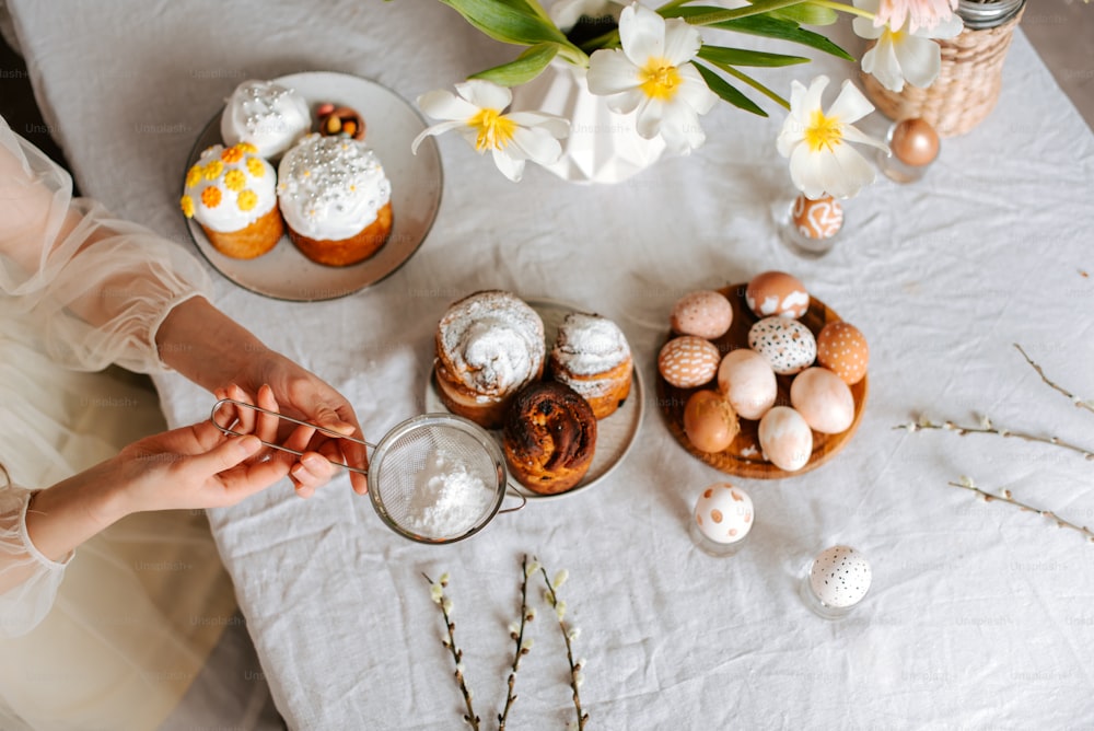 uma mesa coberta com bolos e cupcakes em cima de uma toalha de mesa branca
